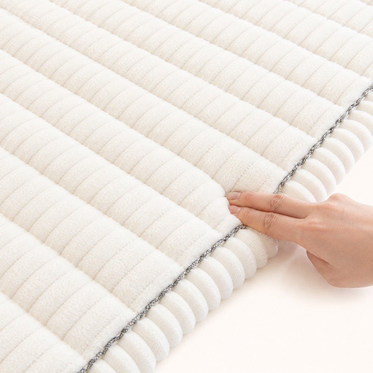 Close-up of the cream ribbed plush pet couch cover with softly padded channels